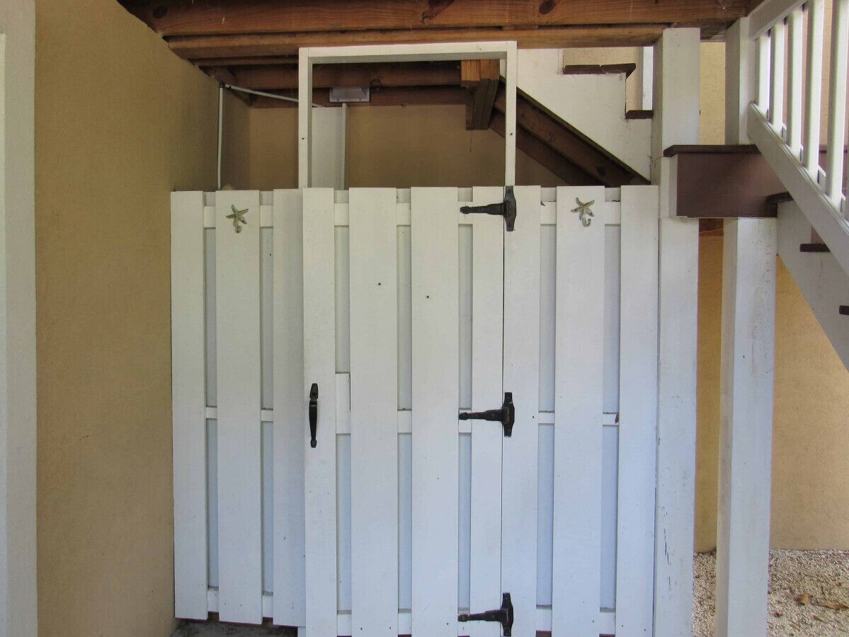Een witte poort met twee zwarte handgrepen en een kleine sterdecoratie aan weerszijden.
