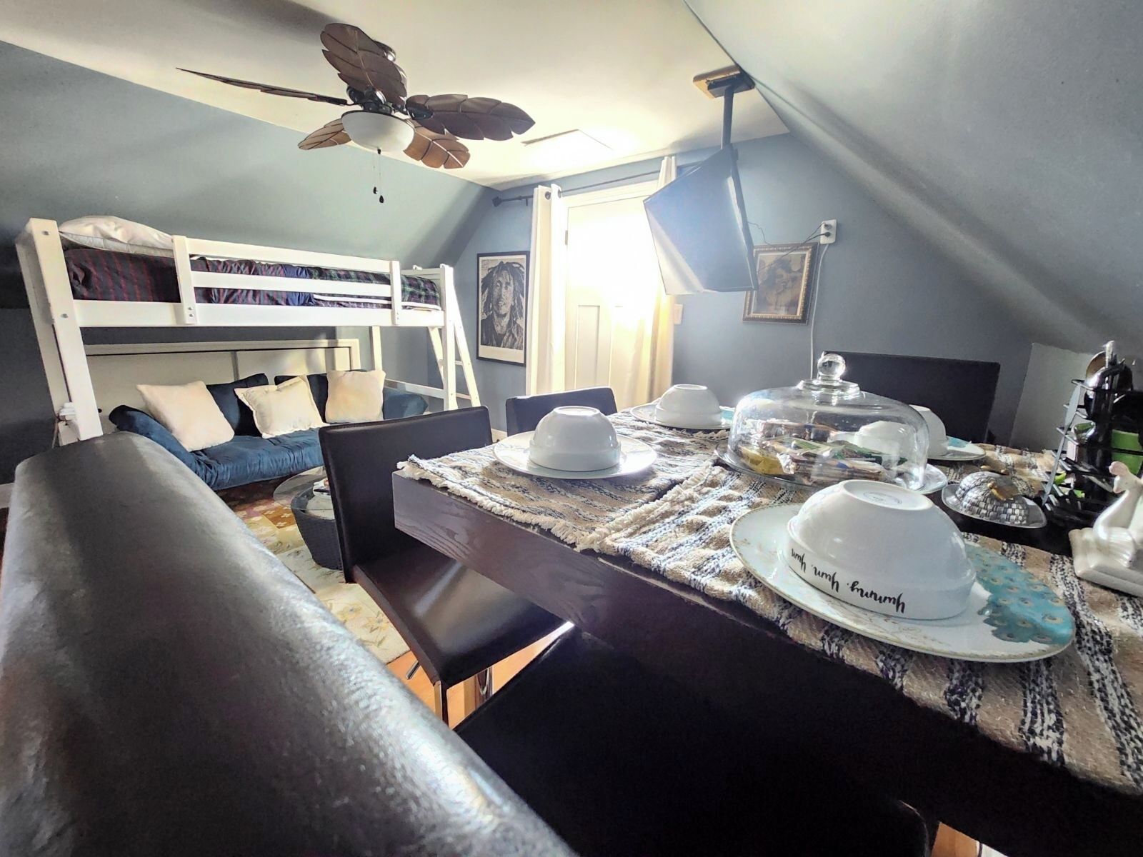 Ein gemütliches Zimmer mit Etagenbett, Esstisch gedeckt mit Geschirr und Deckenventilator.