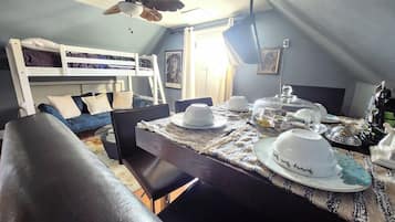 Ein gemütliches Zimmer mit Etagenbett, Esstisch gedeckt mit Geschirr und Deckenventilator.