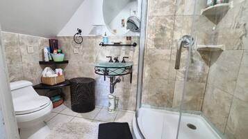 A bathroom with a toilet, sink, shower, and a mirror.