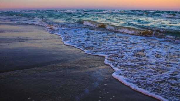 A beach with waves gently lapping onto the shore. - 2Bed2Bath, sleeps 6. Pet friendly. Pool. Hot tub. walking distance to the beach. (Corpus Christi)