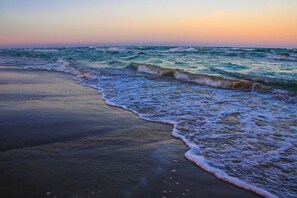 A beach with waves gently lapping onto the shore. - 2Bed2Bath, sleeps 6. Pet friendly. Pool. Hot tub. walking distance to the beach. (Corpus Christi)