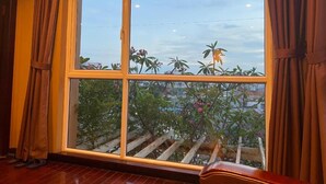 A room with a large window, curtains, and a view of greenery outside. - Ha Noi Le Grand Hotel (Hanoi)