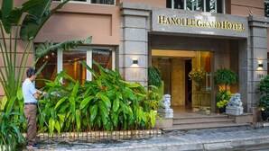 The Hanoi Grand Hotel facade with a large entrance, a stone statue, and lush greenery. - Ha Noi Le Grand Hotel (Hanoi)