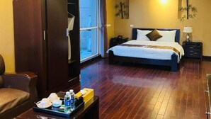 A hotel room with a bed, a wardrobe, a desk with toiletries, and a ceiling fan. - Ha Noi Le Grand Hotel (Hanoi)