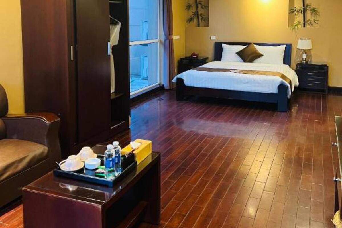 A hotel room with a bed, a wardrobe, a desk with toiletries, and a ceiling fan.