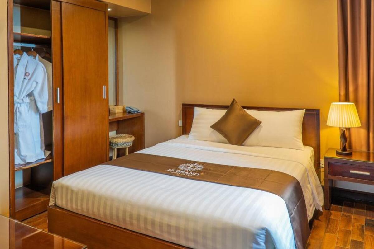 A hotel room with a bed, a wardrobe, a bedside table, and a lamp.