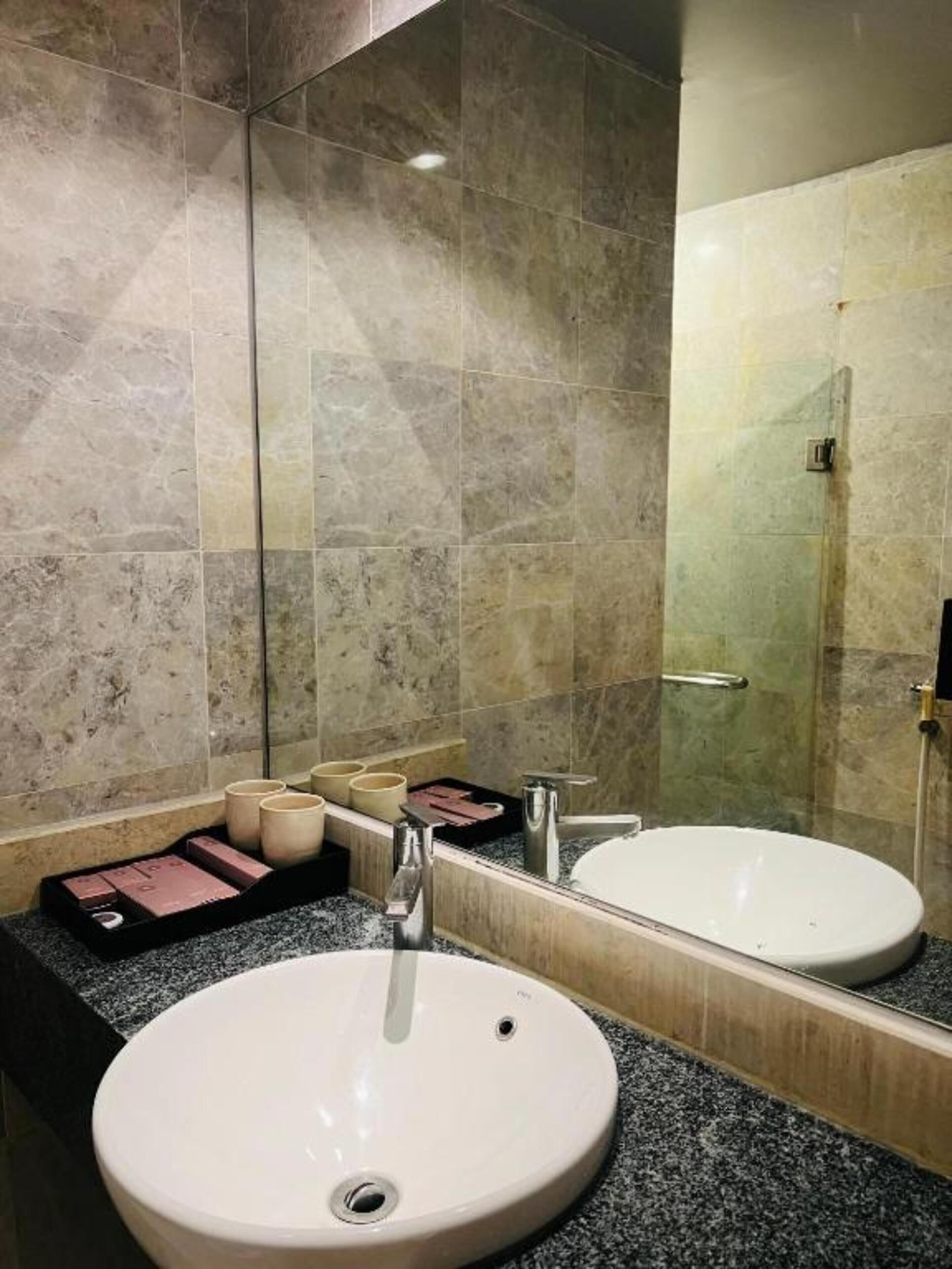 Ein Badezimmer mit einem weißen Waschbecken, einem Spiegel und einer Dusche.