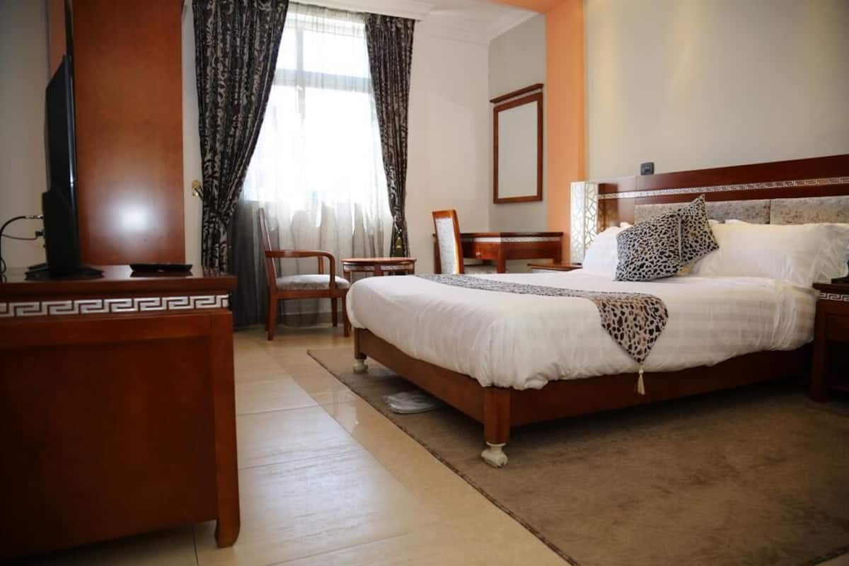 Une chambre d’hôtel avec un grand lit, un bureau, une chaise et un téléviseur.