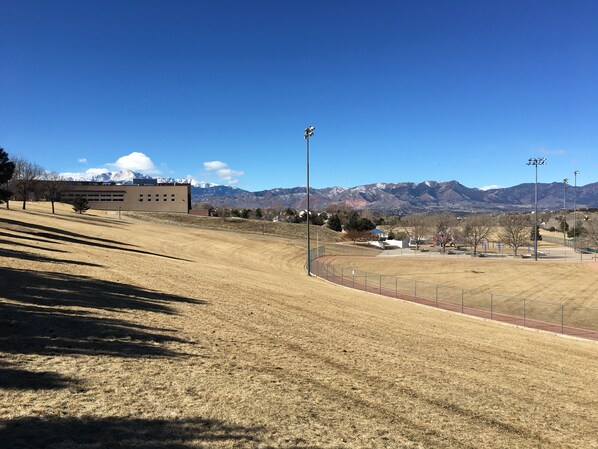 Un campo de deportes con pista de atletismo, un edificio y montañas al fondo.