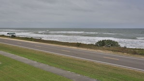 Una strada costiera con un guardrail, un piccolo riparo e vista sull'oceano.