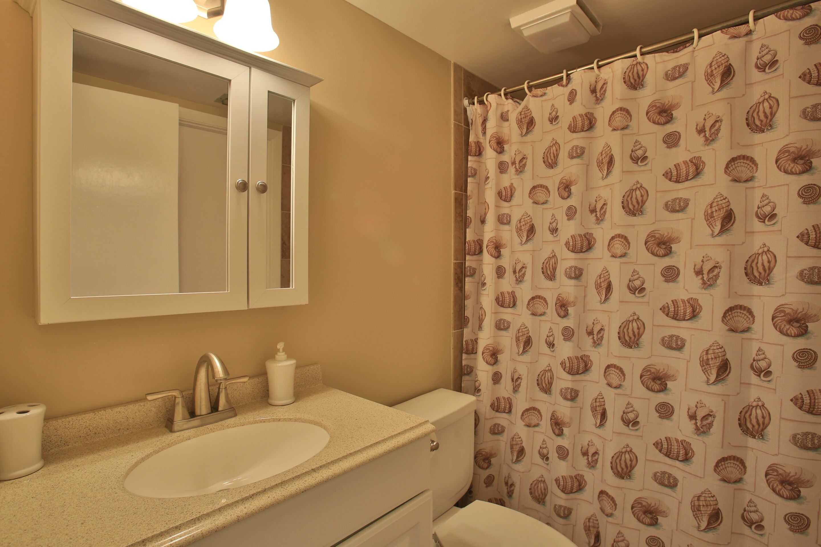 Une salle de bain avec un lavabo, un miroir et des toilettes.