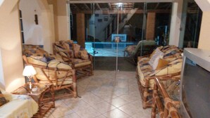 A room with wicker furniture, a glass door leading outside, and a tiled floor. - Rancho - Mini stud farm with swimming pool and barbecue! (Sao pedro)