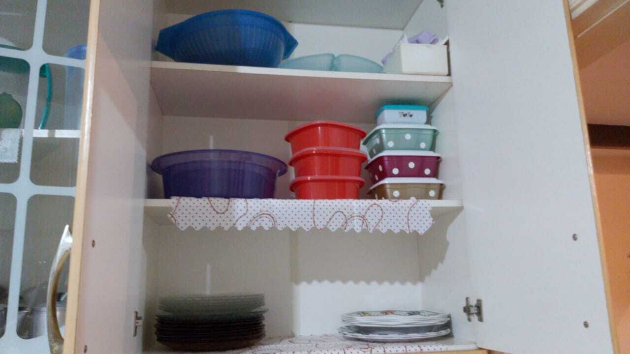A storage cabinet with multiple shelves, some containing plastic containers and others holding stacks of plates.