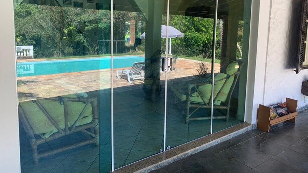 A glass-enclosed patio with a pool, outdoor furniture, and a ceiling fan. - Rancho - Mini stud farm with swimming pool and barbecue! (Sao pedro)