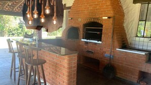 A brick outdoor kitchen with a pizza oven, bar stools, and a hanging light fixture. - Rancho - Mini stud farm with swimming pool and barbecue! (Sao pedro)