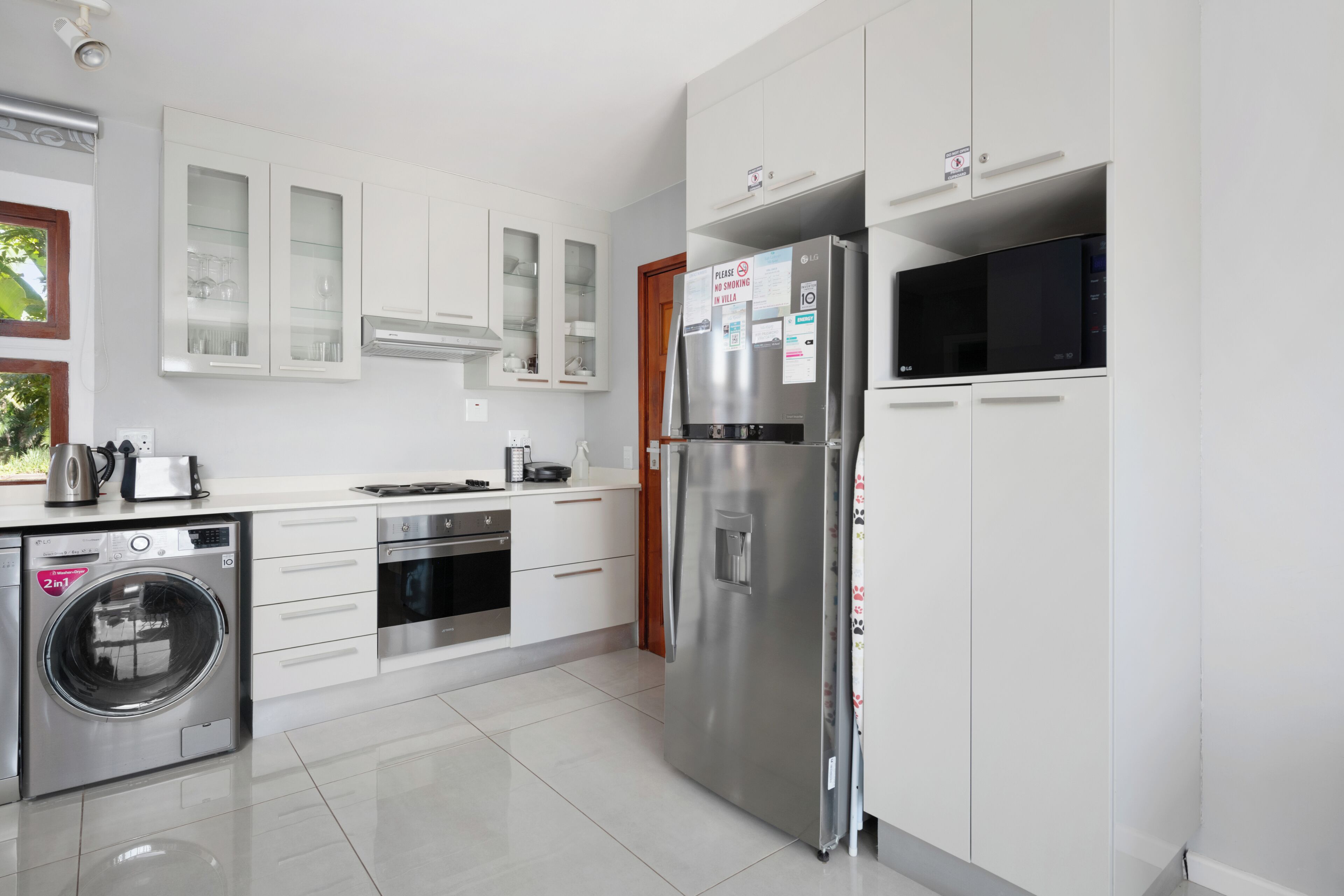 A modern kitchen with stainless steel appliances, white cabinetry, and a built-in washing machine.