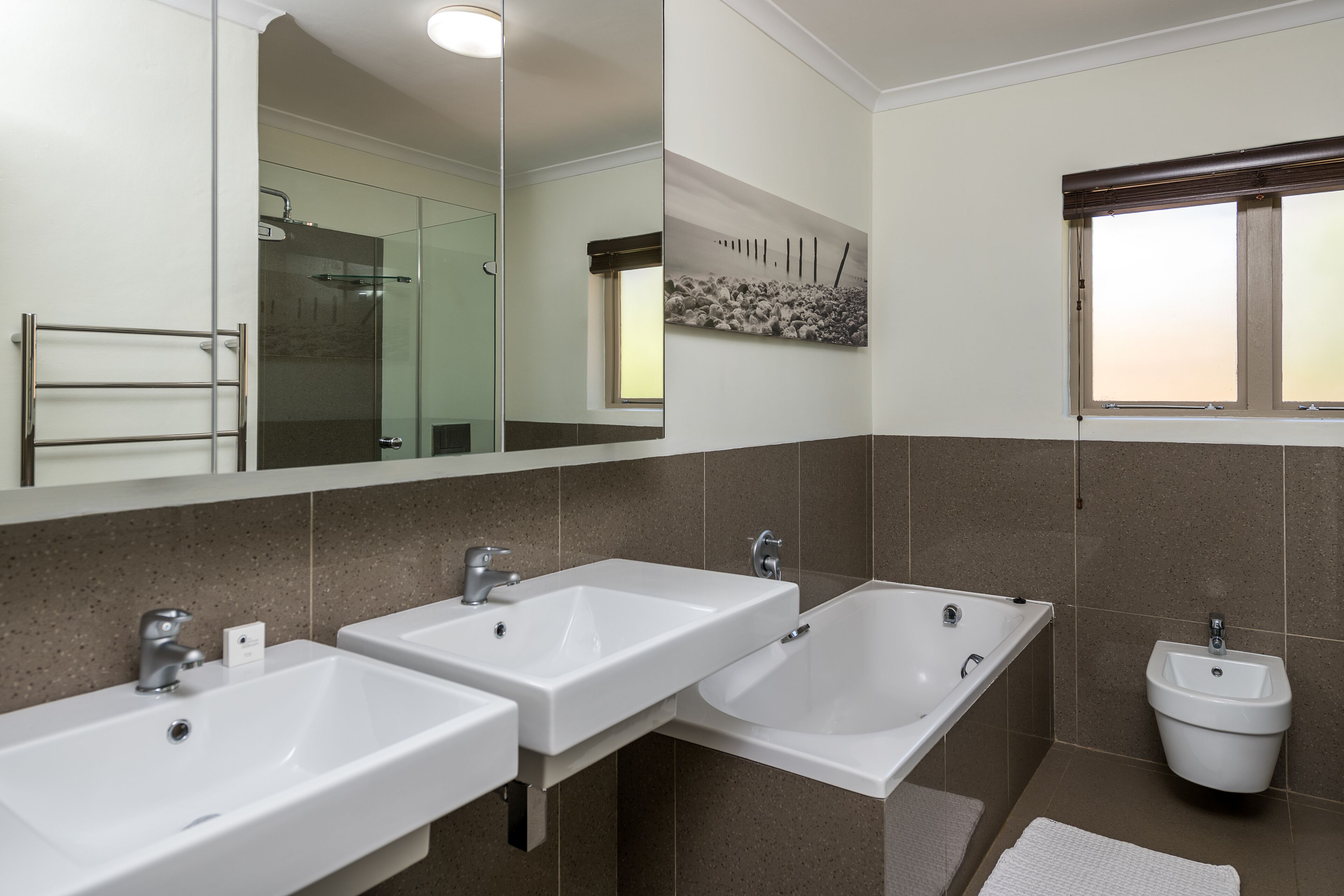 Une salle de bain moderne avec deux lavabos, une baignoire et un bidet.