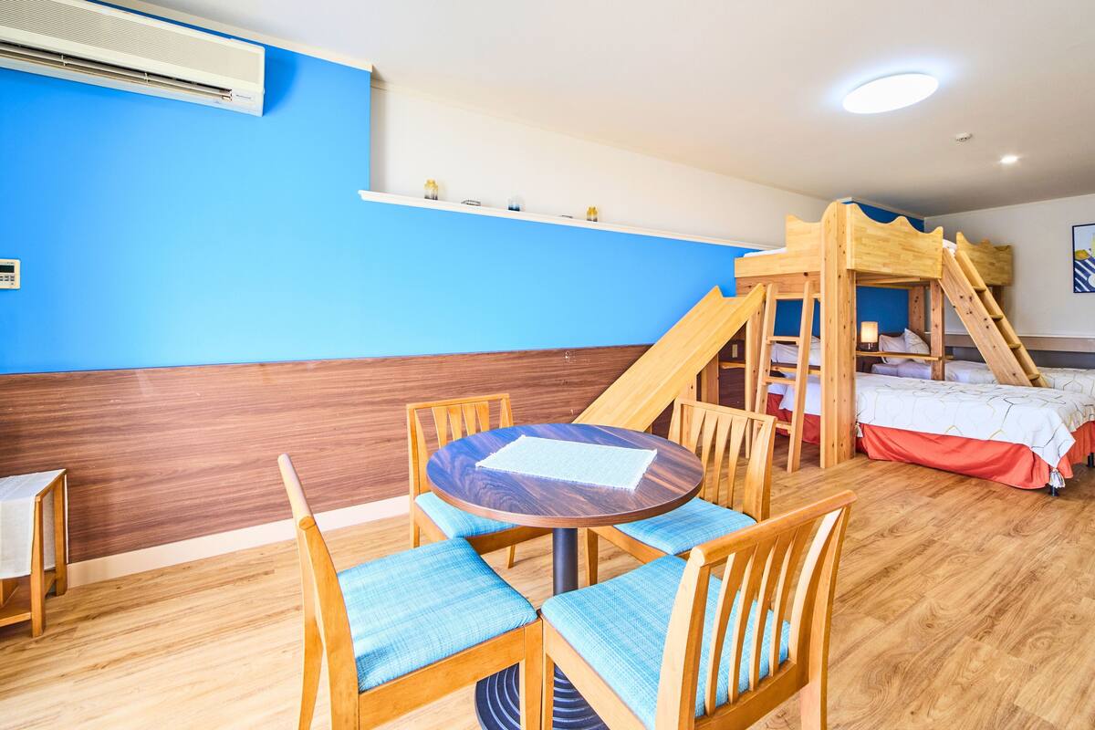 A children's play area with a bunk bed, a table with chairs, and a blue wall.