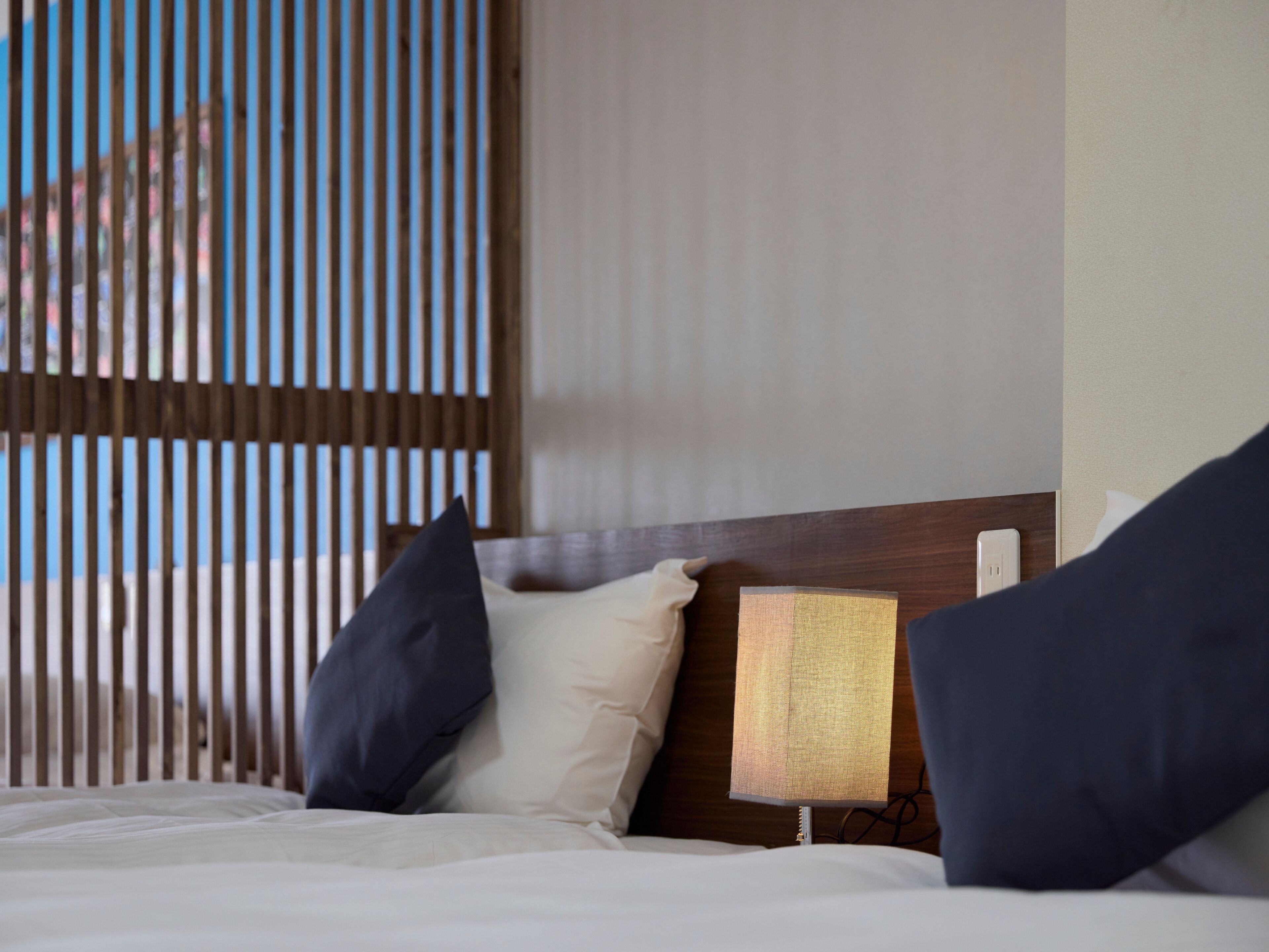 Une chambre d’hôtel avec un lit, des oreillers, une table de chevet et une lampe.