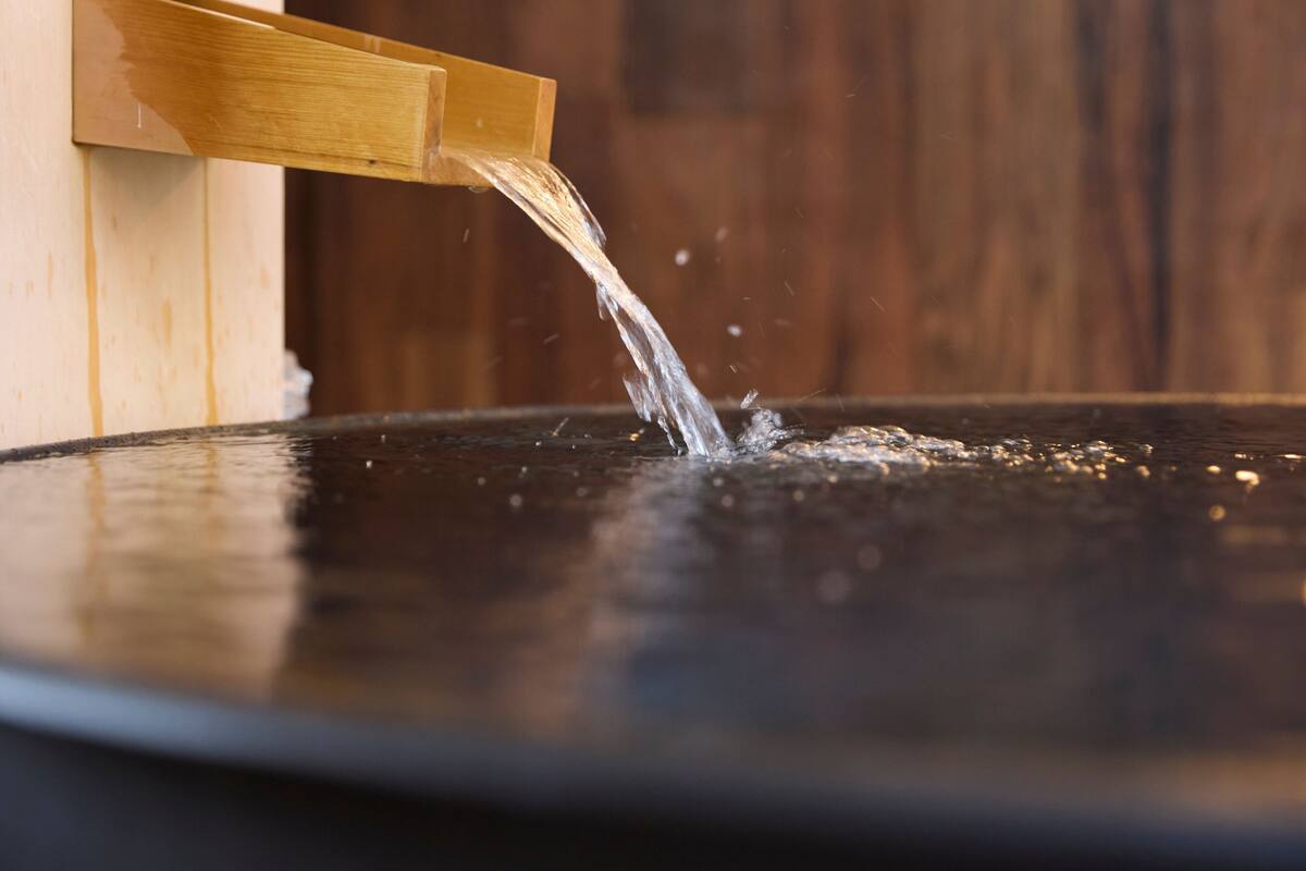 A wooden water feature with water flowing into a dark basin.