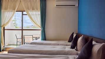 A hotel room with two beds, a balcony with a table and chairs, and an air conditioning unit on the wall.