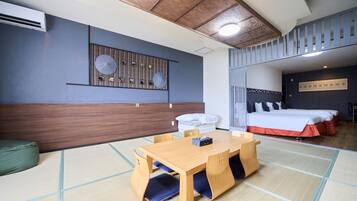 A hotel room with a tatami mat floor, a wooden table with chairs, a bed with white bedding, a wall-mounted air conditioner, and a ceiling with wooden panels and recessed lighting.