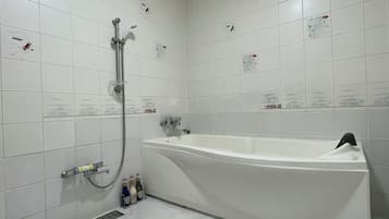 A bathroom with a bathtub, a shower, and a hand dryer.