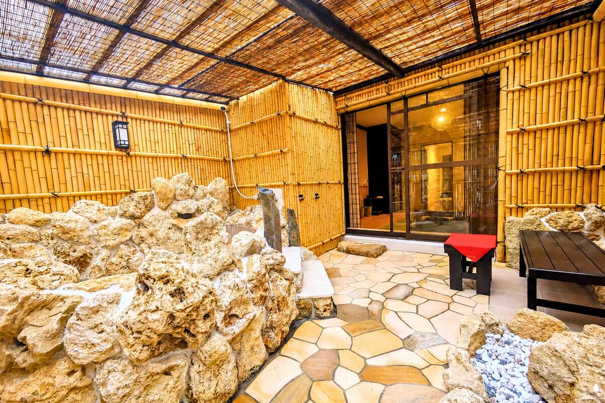 A bamboo-walled room with a stone floor, a bench, and a table.