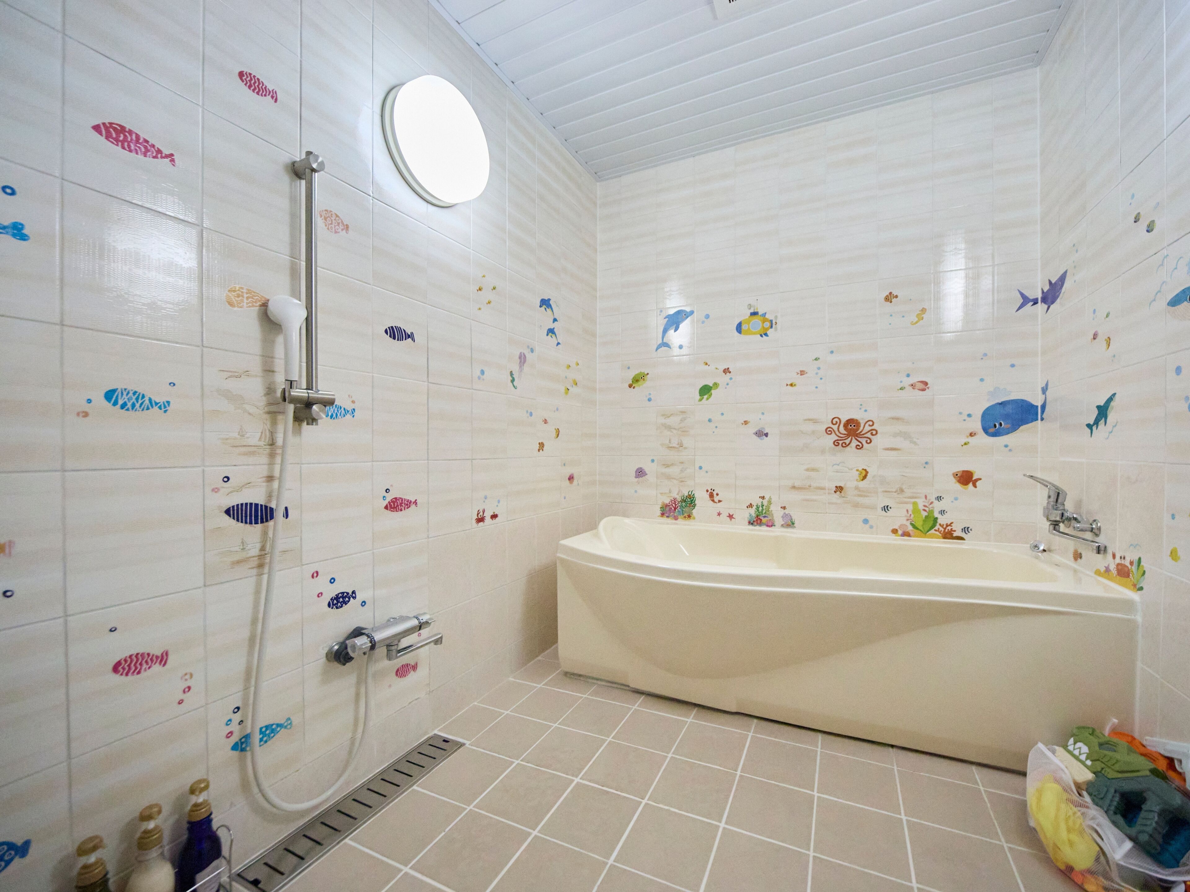 Ein Badezimmer mit Badewanne, Dusche und Haltegriffen.