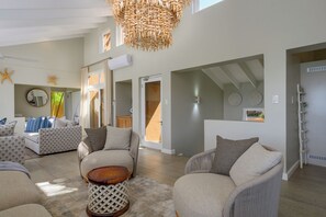 A spacious living area with a high ceiling, a large woven light fixture, and a view of the outdoors through a sliding door. - San Lameer Villa Rentals 13917 (Southbroom)