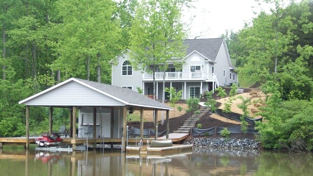 Une maison avec un quai et un espace abrité au bord d’un lac.