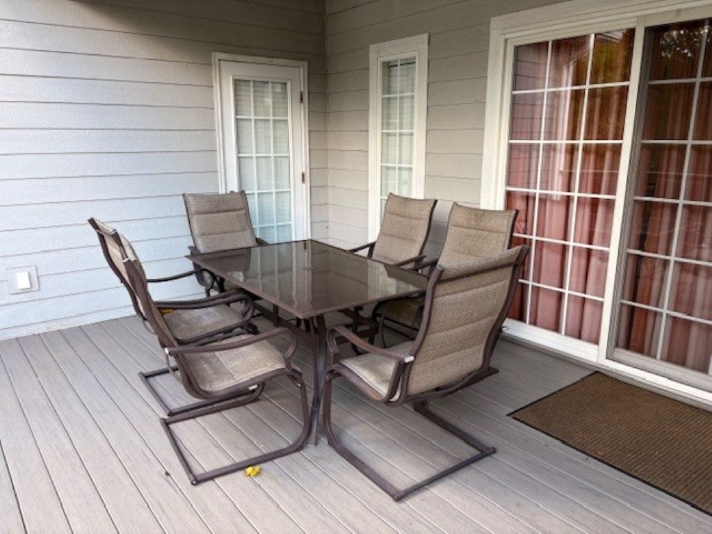 A covered patio with a glass-top table and six chairs.