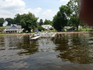 A lake with a dock and boats, surrounded by houses and trees.
