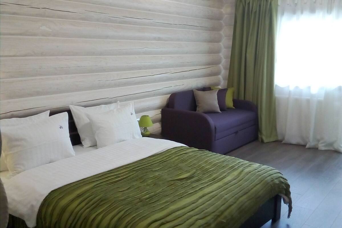 Una habitación con cama, sofá y ventana con cortinas.