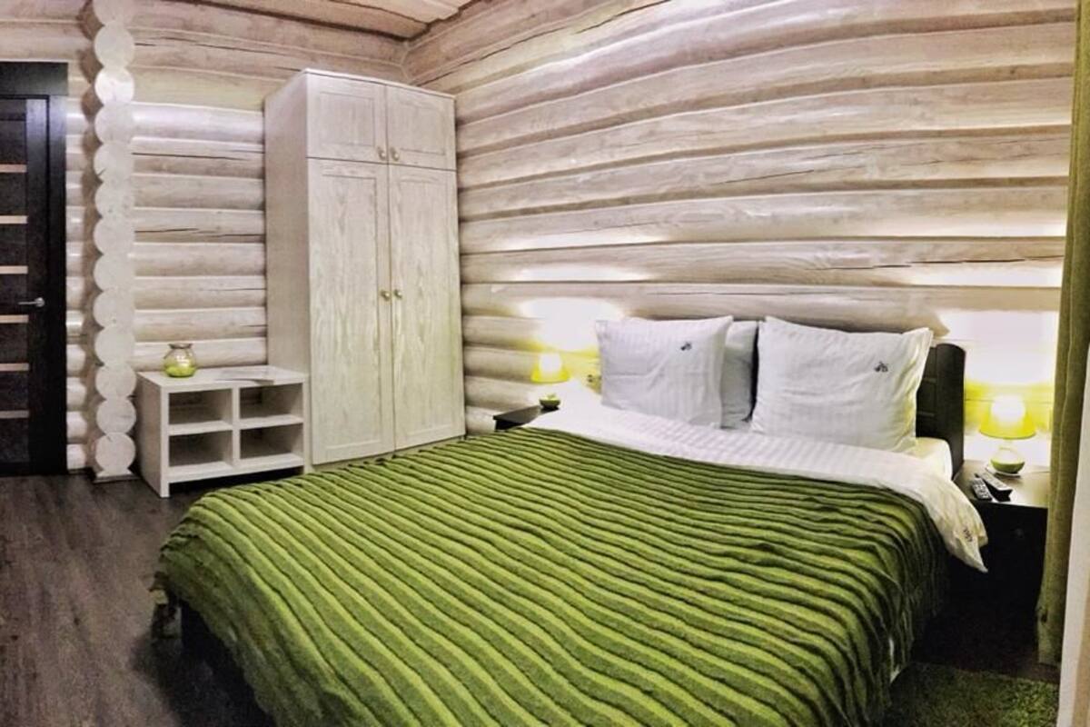 Un dormitorio de estilo cabaña de madera con cama, armario y una puerta.