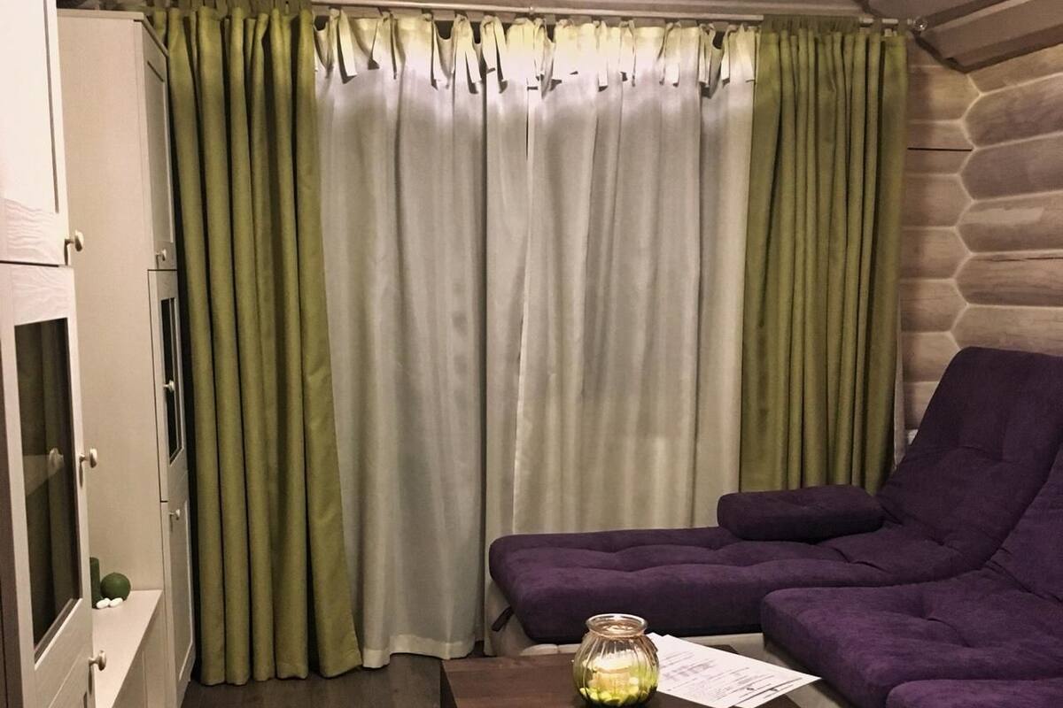 Un espacio habitable compacto con un sofá púrpura, una mesita de madera y un tapete verde.