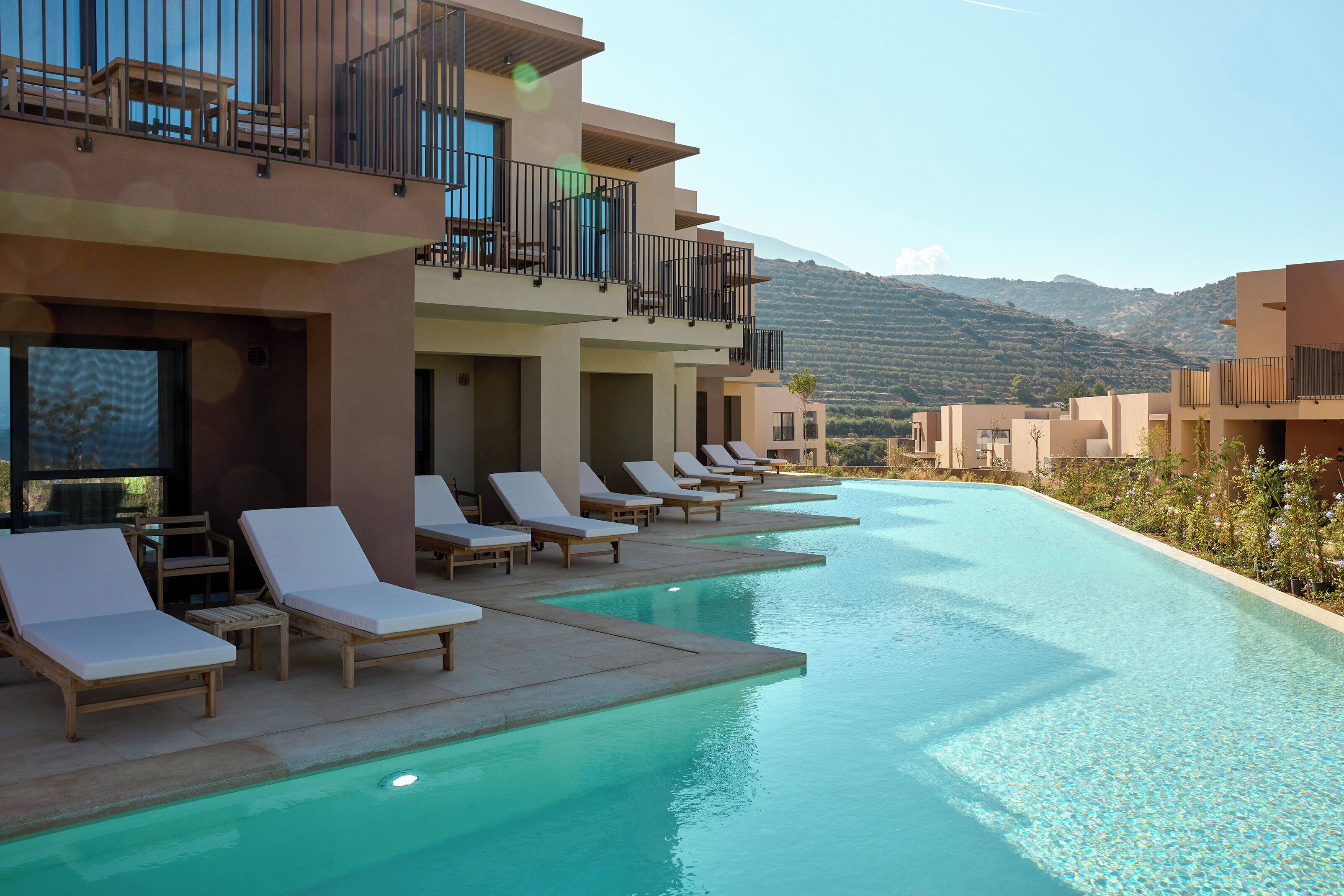 A poolside area with lounge chairs and a view of mountains.