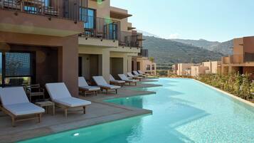 A poolside area with lounge chairs and a view of mountains.