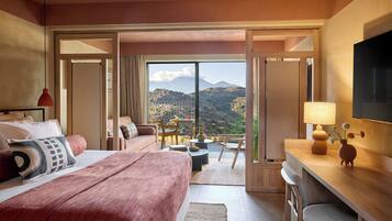 A hotel room with a large bed, a desk, a chair, a TV, and a balcony with a mountain view.