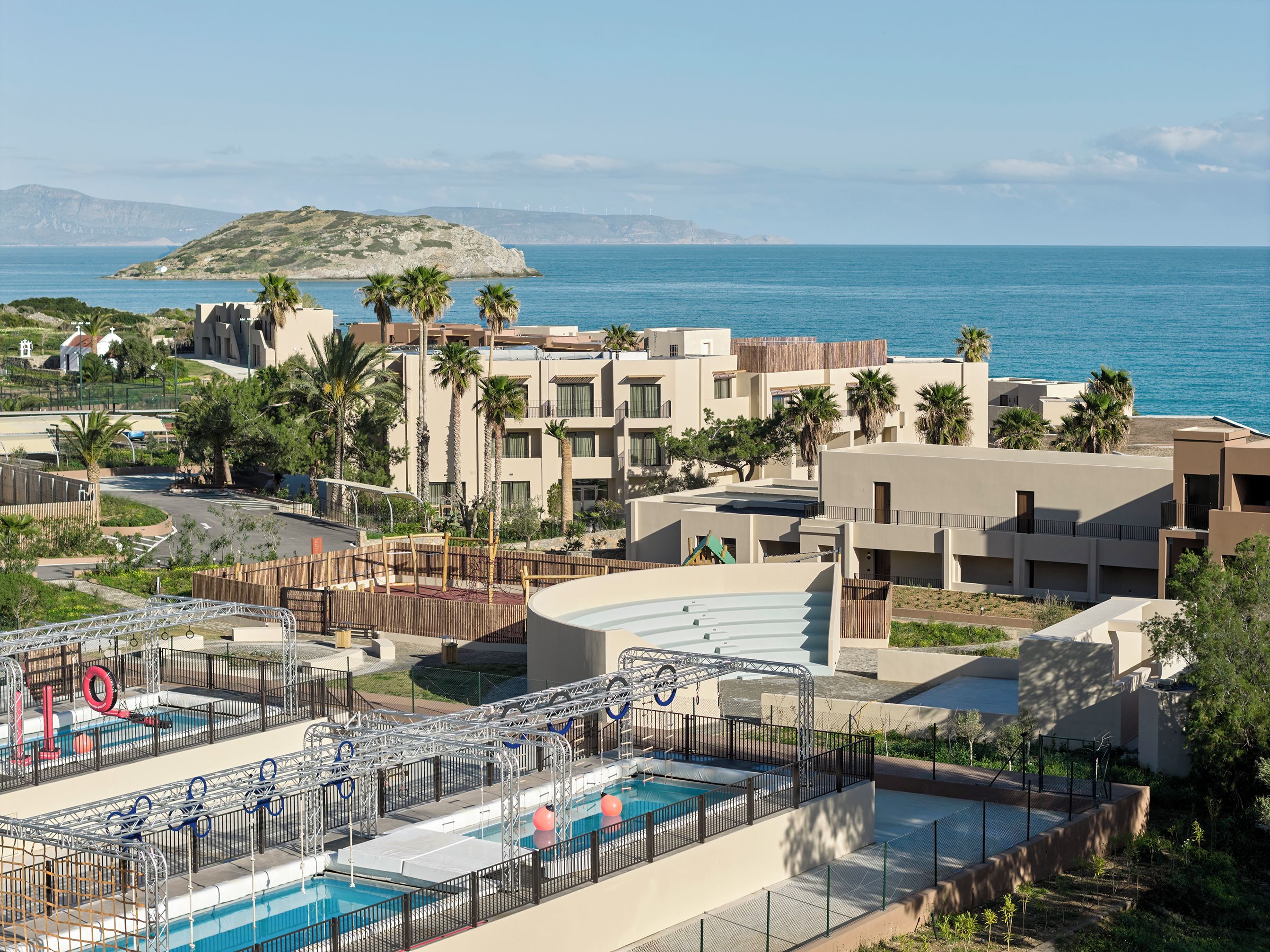 Un complexe hôtelier doté d’une piscine, de palmiers et offrant une vue sur la mer.