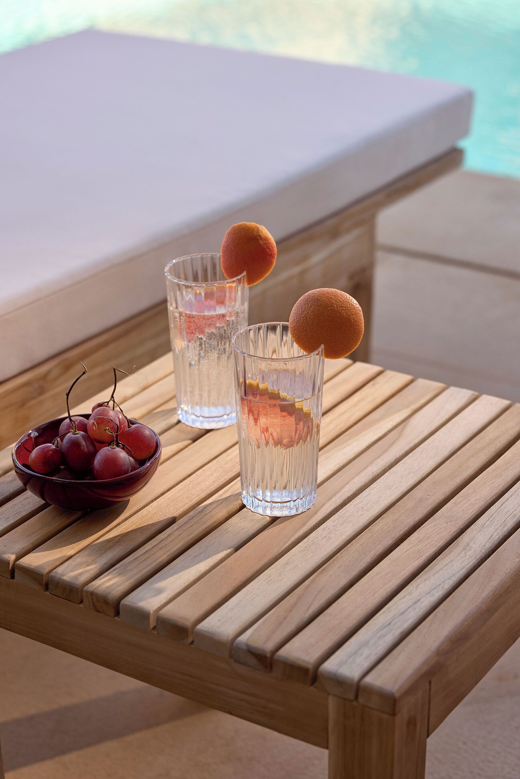 Una mesa de madera con dos vasos de agua y un bol de cerezas.