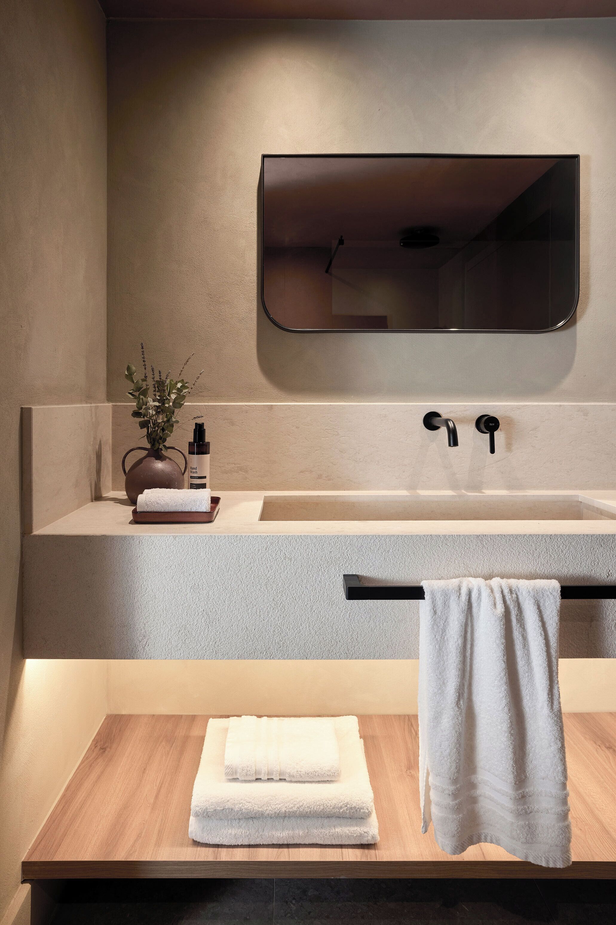 A modern bathroom with a large mirror, a sink, and a wooden vanity.