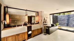 A modern bathroom with a large mirror, dual sinks, wooden cabinetry, and a view of a water feature. - Tamarind Exclusive Villa (Sattahip)
