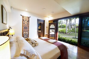 A hotel room with a bed, a lamp, a curtain, and a view of the garden through a glass door. - Tamarind Exclusive Villa (Sattahip)