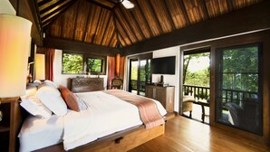 A spacious bedroom with a large bed, wooden ceiling, and a balcony with a view of trees. - Tamarind Exclusive Villa (Sattahip)
