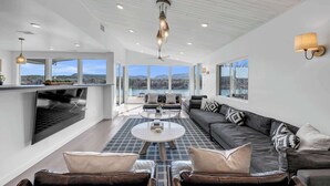 A spacious living area with a large sofa, a coffee table, and a television mounted on the wall.