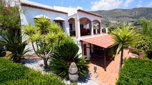 A white villa with a red-tiled roof, surrounded by lush greenery and a mountainous backdrop. - Great Villa ideal for groups: swimming pool, wifi, air conditioning, sea view. (Frigiliana)