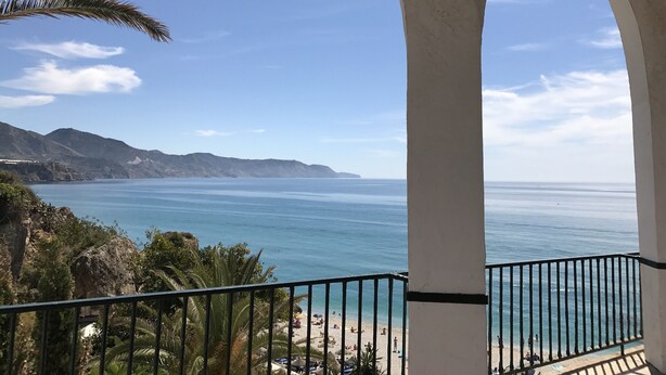 A coastal view from a balcony with a railing, overlooking a beach with people and umbrellas. - Great Villa ideal for groups: swimming pool, wifi, air conditioning, sea view. (Frigiliana)