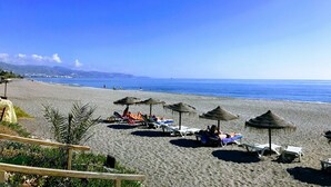 A beach with sun loungers and thatched umbrellas, a clear sky, and a calm sea. - Great Villa ideal for groups: swimming pool, wifi, air conditioning, sea view. (Frigiliana)
